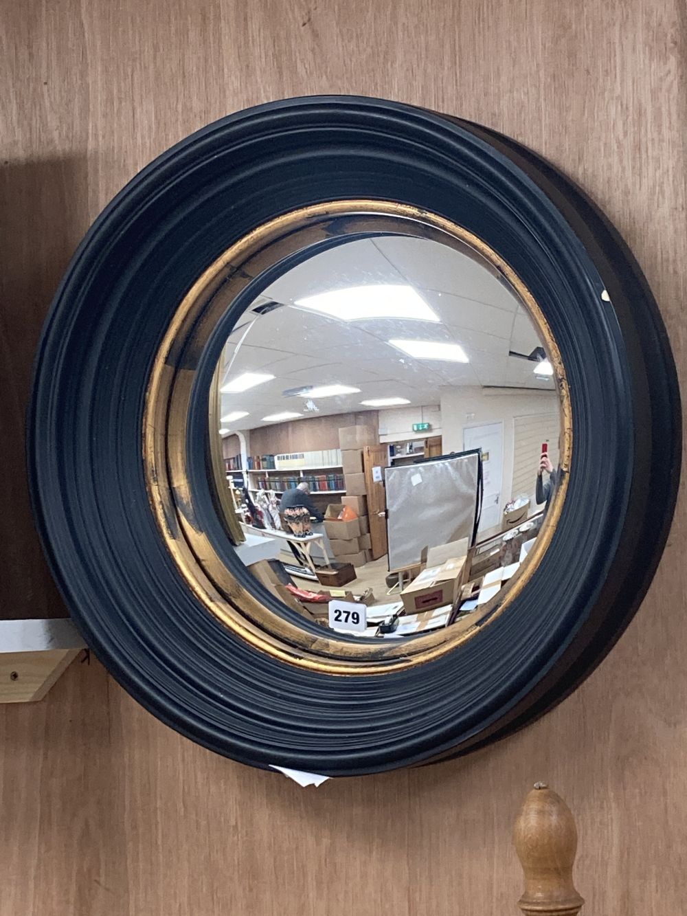 An ebonised framed convex mirror, with a gilt slip